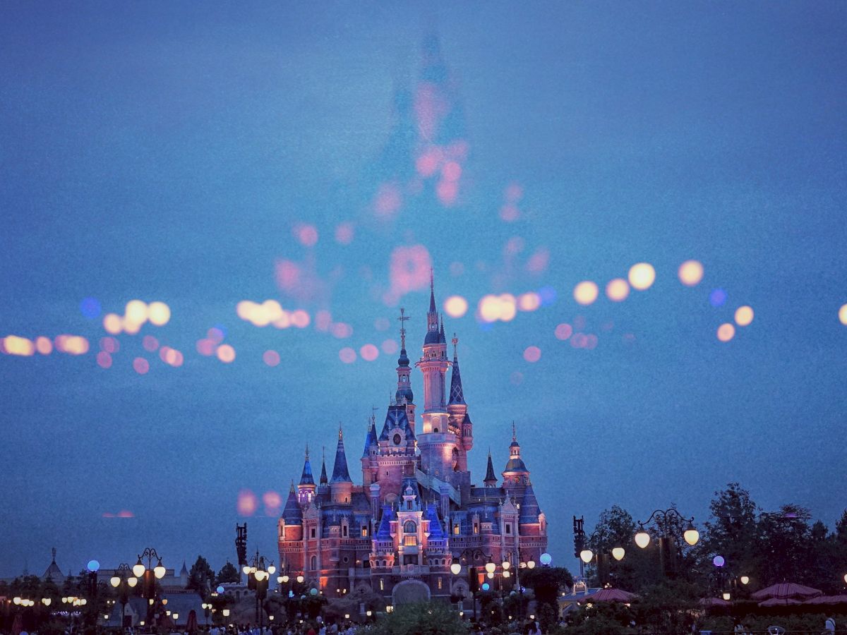 A vibrant image of a lit-up castle at night with a magical overlay of bokeh lights against a dark sky, creating a dreamy atmosphere.