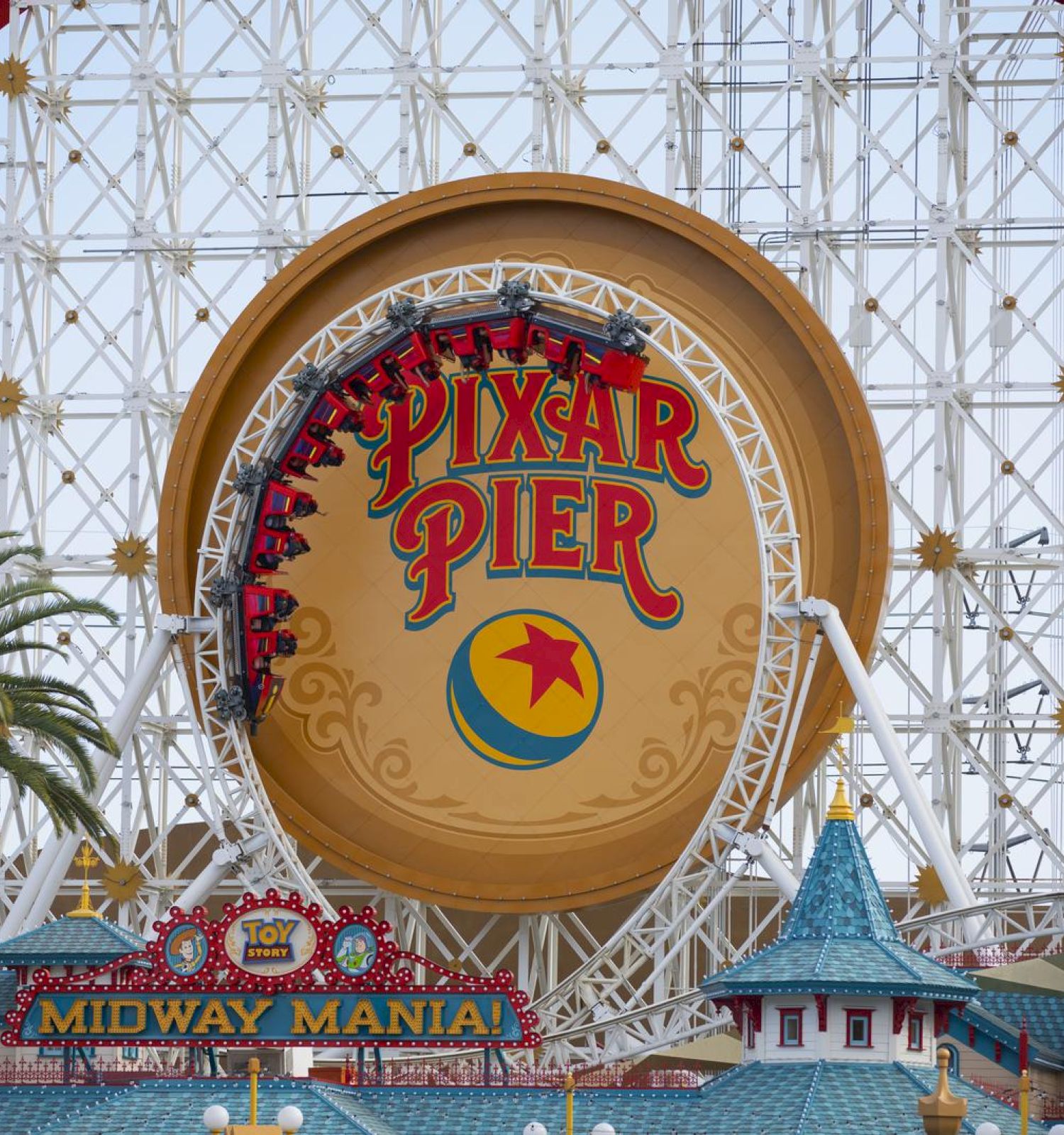 This image shows the Pixar Pier entrance sign with a Ferris wheel structure in the background at a theme park, along with the Midway Mania ride entrance.