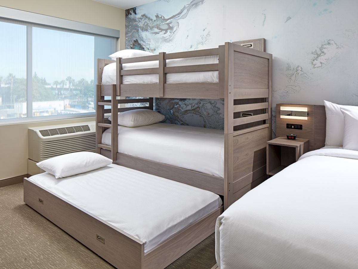 The image shows a modern bedroom with bunk beds, a trundle bed, a large bed, a window, an air conditioner, and a nightstand with a lamp.