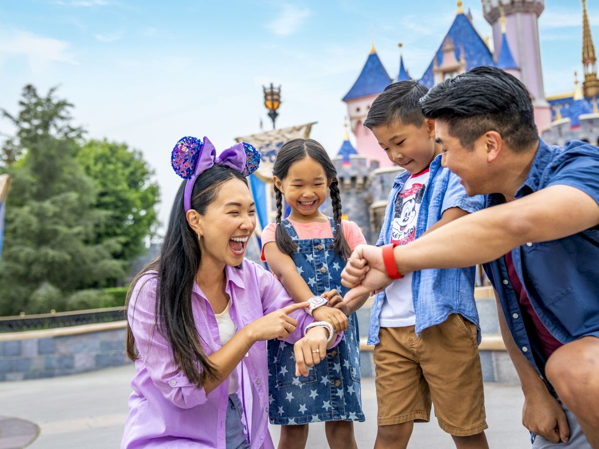 A family having fun, wearing matching wristbands and mouse ears, with a castle in the background, suggesting a theme park visit.
